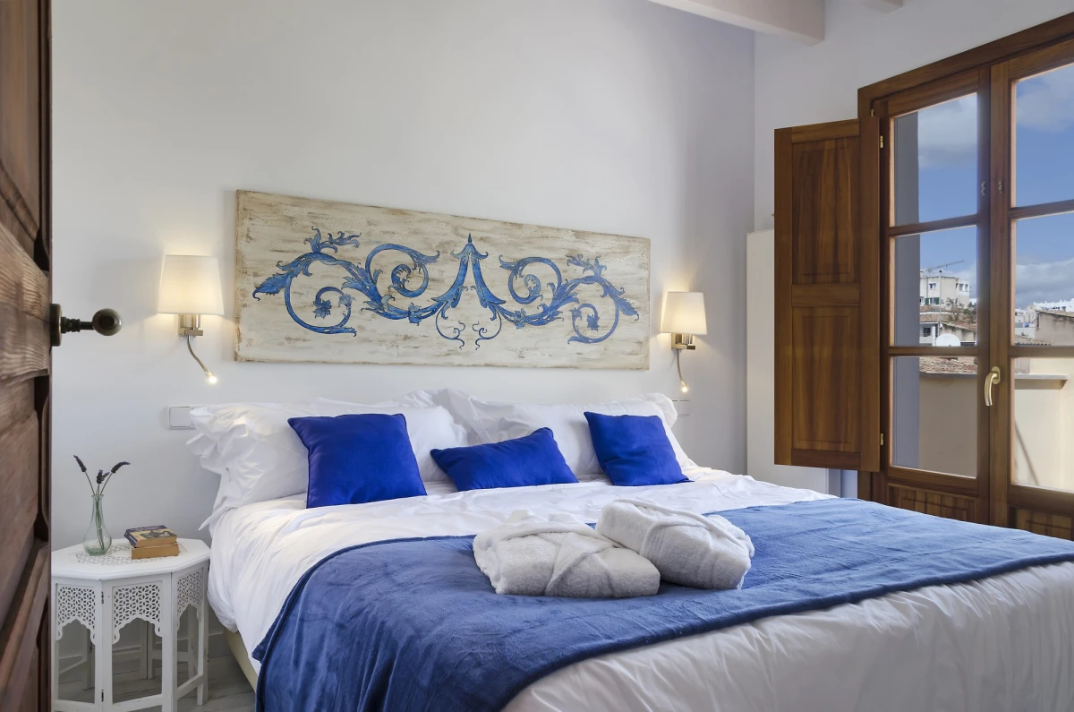 The penthouse bedroom with towels on the bed and doors to the terrace
