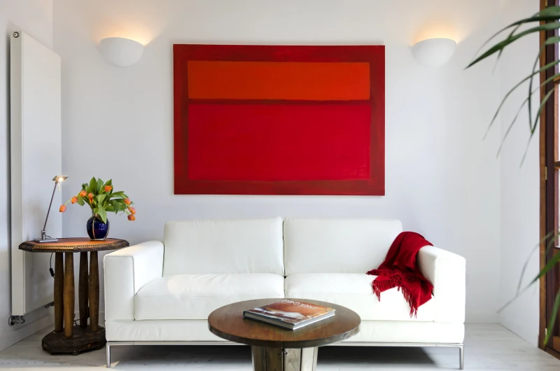 Das Wohnzimmer eines Apartments mit zwei Schlafzimmern, mit einem roten Bild über dem Sofa