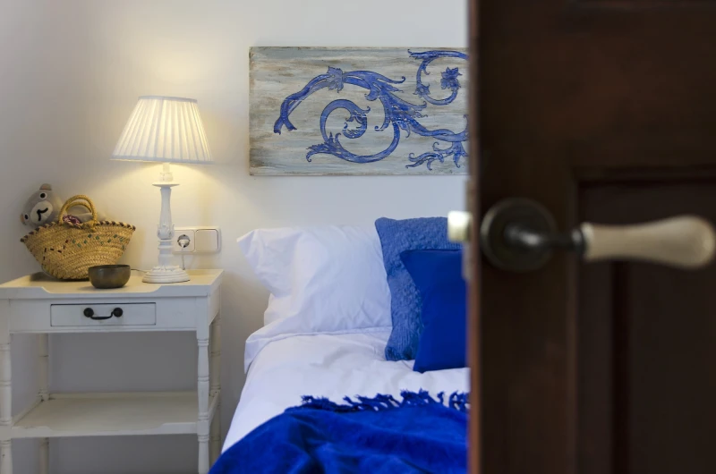 A bed with blue cushions seen through the bedroom door