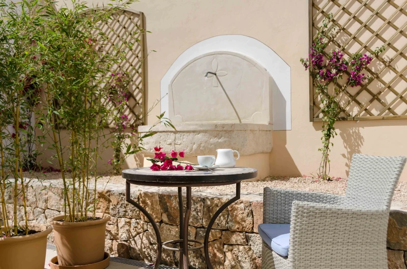 A cup of coffee on a patio table in front of the stone fountain